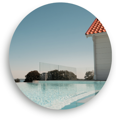 Stolpefritt glassrekkverk montert ved et moderne utendørs basseng. Gir fri utsikt mot landskap og trygg innramming uten å hindre utsynet. Perfekt som sikkerhetsrekkverk til basseng eller terrasse.