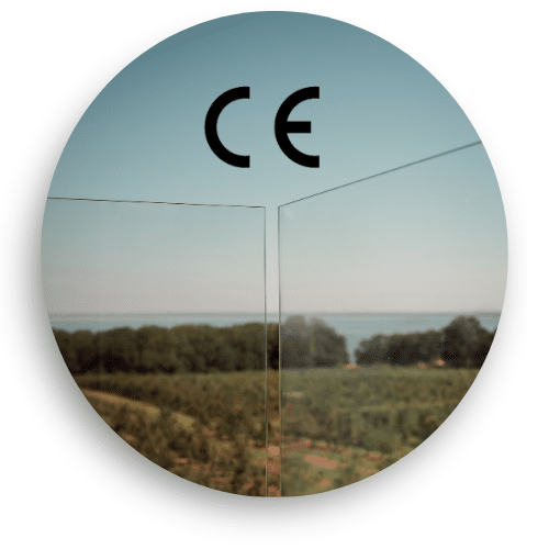 Nærbilde av CE-merket laminert sikkerhetsglass brukt i bassengrekkverk – med fri utsikt over skånsk kulturlandskap.